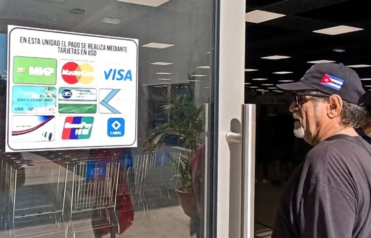 Un hombre observa el cartel con las tarjetas magnéticas que pueden usarse para realizar compras en el nuevo el Supermercado de 3ra y 70, en La Habana. Foto: Ernesto Mastrascusa / EFE.