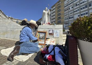 Un artista dibuja ante la escultura del papa Juan Pablo II, a las puertas del Hospital Gemelli donde permanece ingresado el papa  Francisco. Foto:  EFE/Daniel Cáceres