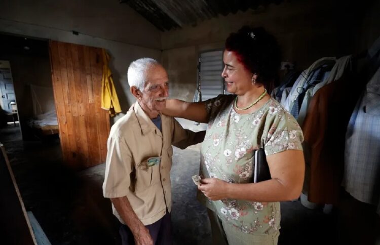 Un anciano que vive solo conversa con una trabajadora del Centro Cristiano de Reflexión y Diálogo (CCRD), en Cárdenas, Matanzas. Foto: Ernesto Mastrascusa / EFE.