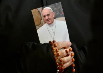 Una monja sostiene una imagen del papa Francisco y un rosario mientras los fieles asisten a una oración por su salud en la Plaza de San Pedro en la Ciudad del Vaticano. Foto: EFE/EPA/ALESSANDRO DI MEO.