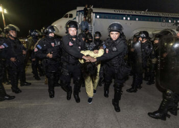 Fotografía cedida por la Presidencia de El Salvador donde se observa a policías de la Unidad de Mantenimiento del Orden (UMO) trasladando a supuestos miembros de la banda criminal conocida como Tren de Aragua el domingo 16 de marzo de 2025, en el aeropuerto internacional Óscar Arnulfo Romero, en San Luis Talpa, tras ser deportados desde Estados Unidos. Foto: Presidencia de El Salvador / EFE.