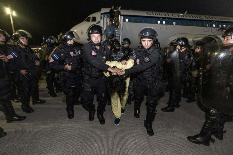 Fotografía cedida por la Presidencia de El Salvador donde se observa a policías de la Unidad de Mantenimiento del Orden (UMO) trasladando a supuestos miembros de la banda criminal conocida como Tren de Aragua el domingo 16 de marzo de 2025, en el aeropuerto internacional Óscar Arnulfo Romero, en San Luis Talpa, tras ser deportados desde Estados Unidos. Foto: Presidencia de El Salvador / EFE.