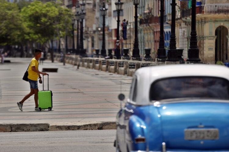 Un hombre con una maleta camina por el paseo del Prado, en La Habana. Foto: Ernesto Mastrascusa/EFE.