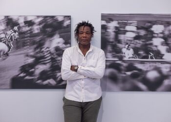 El artista Carlos Torres Cairo flanqueado por fotos suyas que capturan el vértigo del Palio. Foto: Cortesía de Aurelia Ediciones