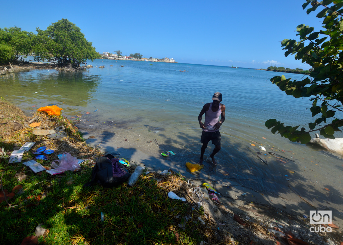 Un hombre limpia botellas plásticas en las aguas de Cojímar. Foto: Otmaro Rodríguez.