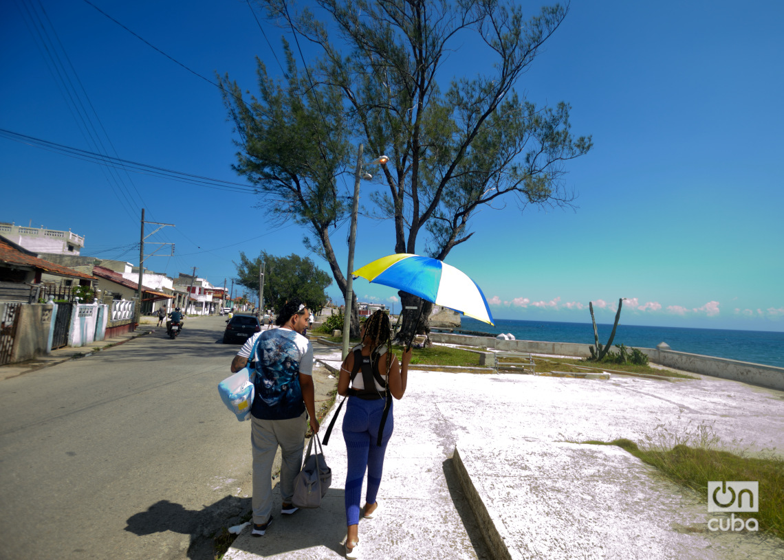 Una pareja camina bajo un intenso sol en el poblado habanero de Cojímar. Foto: Otmaro Rodríguez.