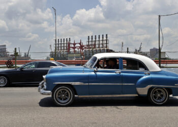 Autos transitan frente a las patanas turcas, generadoras de electricidad, desde la bahía de La Habana. Foto:  Ernesto Mastrascusa/EFE.