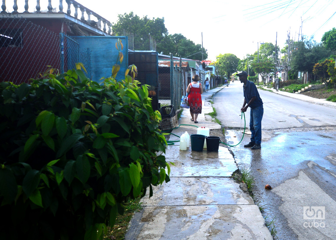Un hombre llena cubos de agua  potable para su casa, en Párraga. Foto: Otmaro Rodríguez.