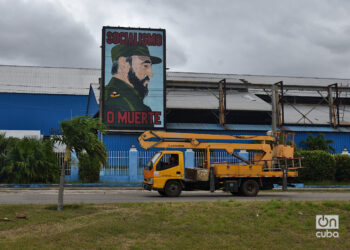 Un camión de la empresa eléctrica pasa cerca de un cartel con la imagen del fallecido expresidente Fidel Castro, en La Habana. Foto: Otmaro Rodríguez.