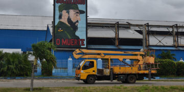 Un camión de la empresa eléctrica pasa cerca de un cartel con la imagen del fallecido expresidente Fidel Castro, en La Habana. Foto: Otmaro Rodríguez.