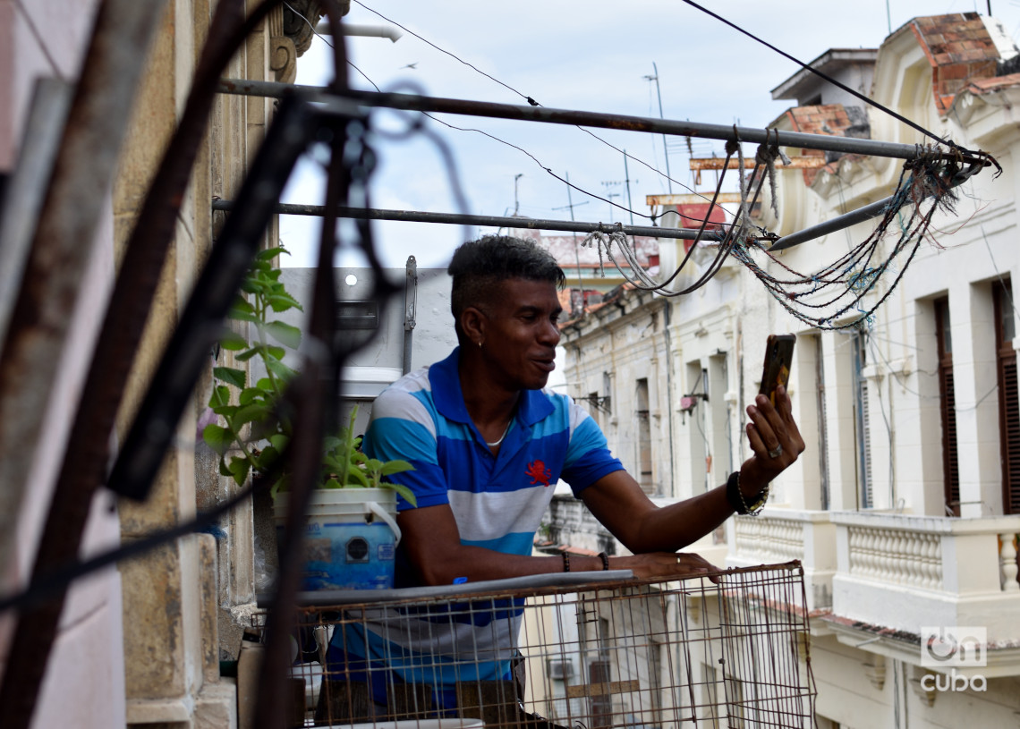 Un hombre se comunica a través de su teléfono celular en el balcón de una vivienda en La Habana, por existir allí mejor señal que en el interior de la casa. Foto: Otmaro Rodríguez.
