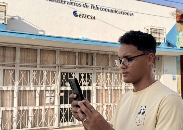 Joven camina frente a una oficina comercial de Etecsa en La Habana. Foto: OnCuba.