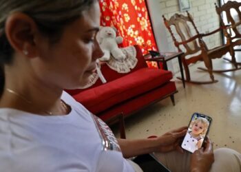 Heidy Sánchez, cubana deportada desde Estados Unidos, observa una foto de su hija durante una entrevista con EFE, en La Habana. Foto: Ernesto Mastrascusa / EFE / Archivo.
