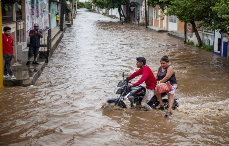 Un motociclista circula por una calle inundada tras el paso del huracán Erick. Foto: Luis Villaobos/EFE.