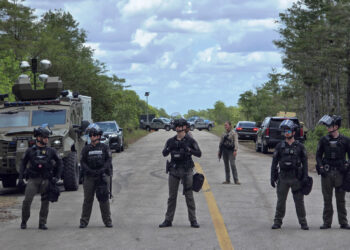 Agentes de la Oficina del Alguacil del Condado de Collier, hacen guardia durante una protesta contra las dependencias migratorias y los centros de detención de inmigrantes en el centro Alligator Alcatraz, en Ochopee. Foto: EFE/ Alberto Boal.