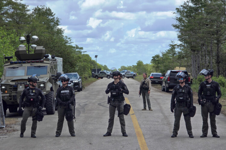 Agentes de la Oficina del Alguacil del Condado de Collier, hacen guardia durante una protesta contra las dependencias migratorias y los centros de detención de inmigrantes en el centro Alligator Alcatraz, en Ochopee. Foto: EFE/ Alberto Boal.