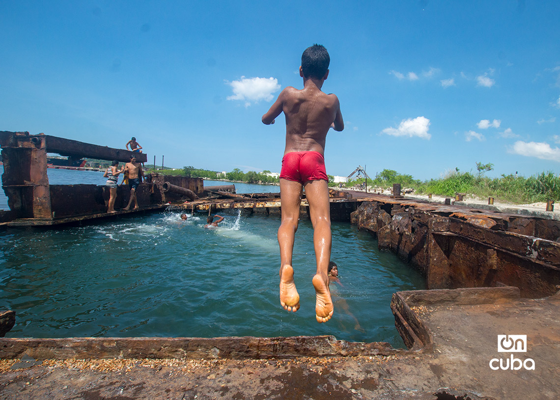 Niños y jóvenes bañándose en una piscina improvisada en una antigua patana en la bahía de La Habana, en Regla. Foto: Otmaro Rodríguez.