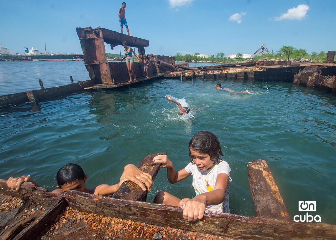 Niños y jóvenes bañándose en una piscina improvisada en una antigua patana en la bahía de La Habana, en Regla. Foto: Otmaro Rodríguez.