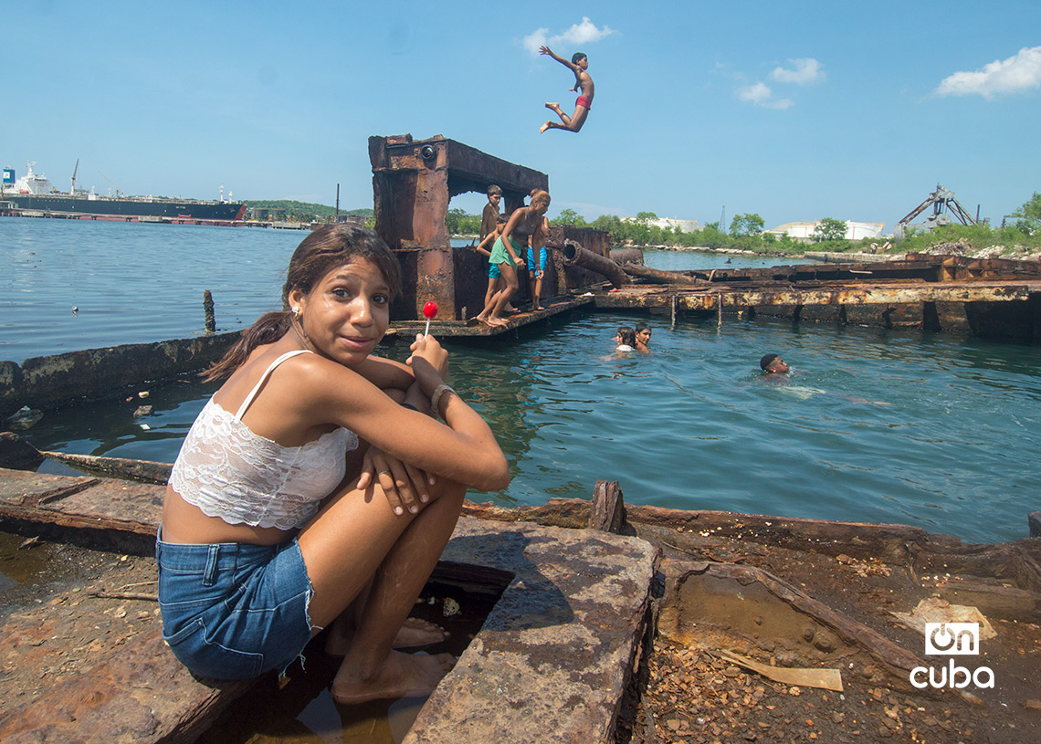 Niños y jóvenes bañándose en una piscina improvisada en una antigua patana en la bahía de La Habana, en Regla. Foto: Otmaro Rodríguez.