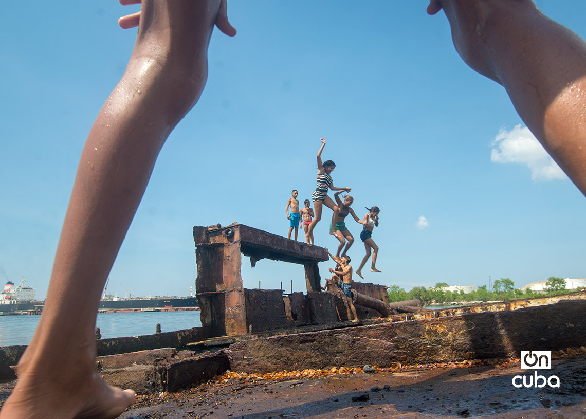 Niños y jóvenes bañándose en una piscina improvisada en una antigua patana en la bahía de La Habana, en Regla. Foto: Otmaro Rodríguez.