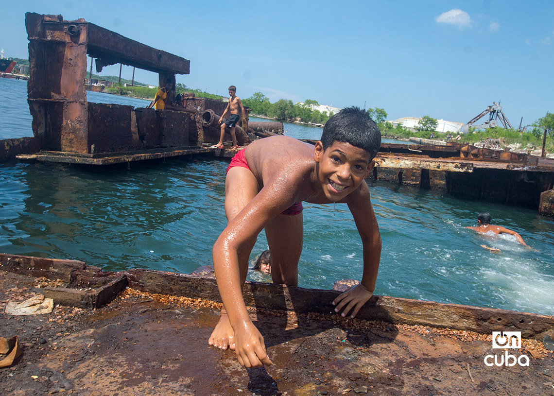 Niños y jóvenes bañándose en una piscina improvisada en una antigua patana en la bahía de La Habana, en Regla. Foto: Otmaro Rodríguez.
