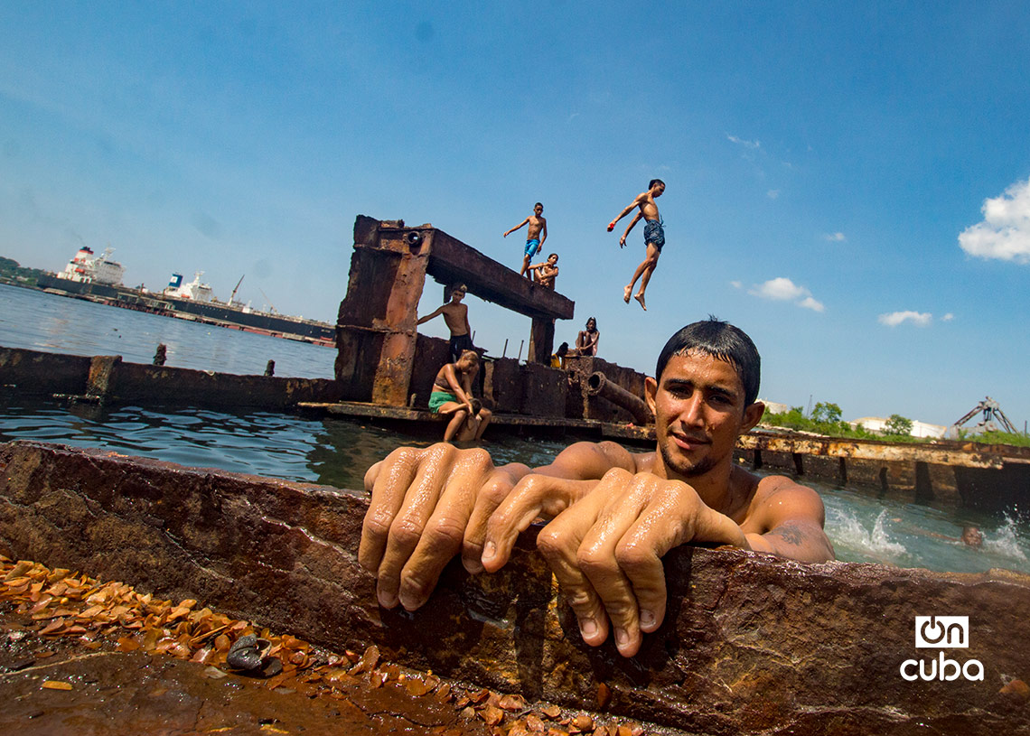 Niños y jóvenes bañándose en una piscina improvisada en una antigua patana en la bahía de La Habana, en Regla. Foto: Otmaro Rodríguez.