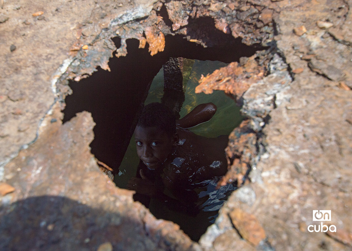 Niños y jóvenes bañándose en una piscina improvisada en una antigua patana en la bahía de La Habana, en Regla. Foto: Otmaro Rodríguez.
