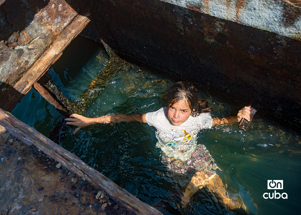 Niños y jóvenes bañándose en una piscina improvisada en una antigua patana en la bahía de La Habana, en Regla. Foto: Otmaro Rodríguez.