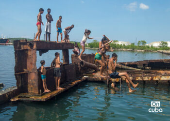 Niños y jóvenes bañándose en una piscina improvisada en una antigua patana en la bahía de La Habana, en Regla. Foto: Otmaro Rodríguez.