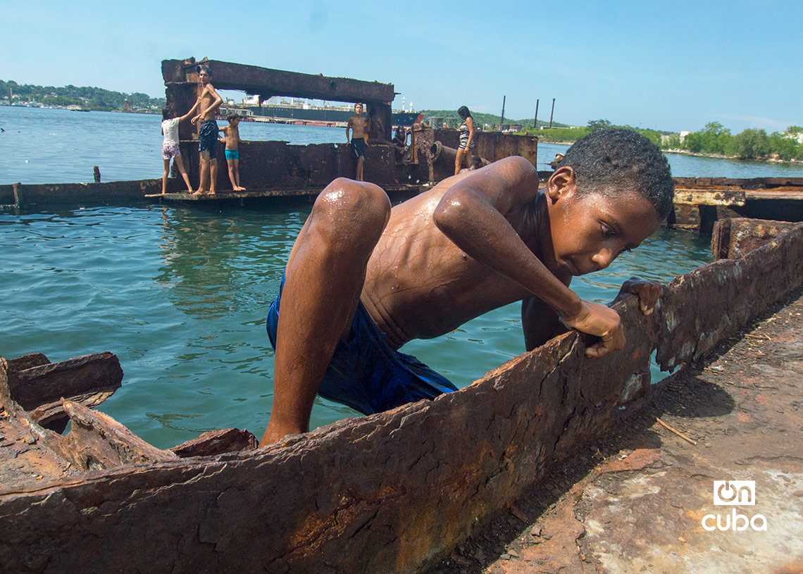 Niños y jóvenes bañándose en una piscina improvisada en una antigua patana en la bahía de La Habana, en Regla. Foto: Otmaro Rodríguez.