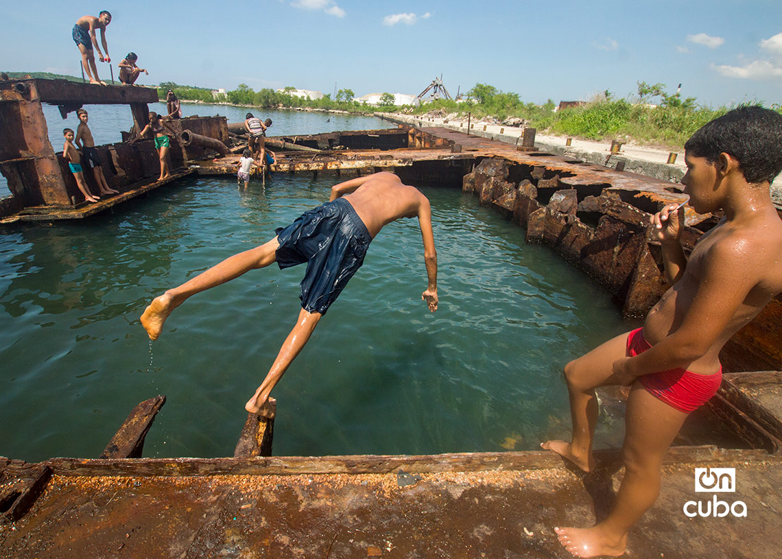 Niños y jóvenes bañándose en una piscina improvisada en una antigua patana en la bahía de La Habana, en Regla. Foto: Otmaro Rodríguez.