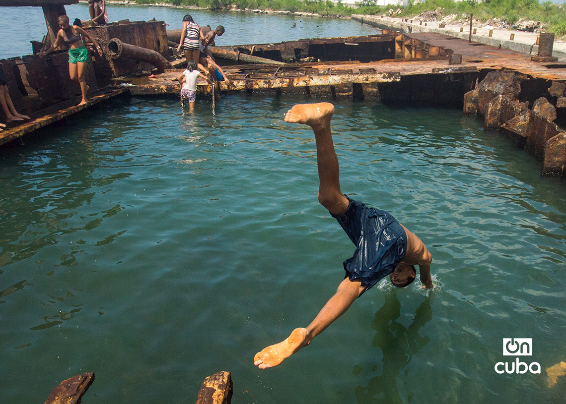 Niños y jóvenes bañándose en una piscina improvisada en una antigua patana en la bahía de La Habana, en Regla. Foto: Otmaro Rodríguez.
