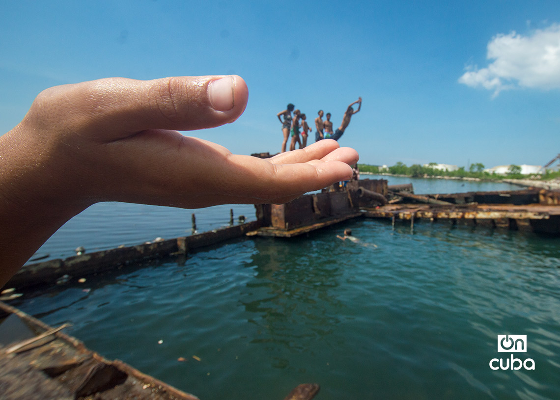 Niños y jóvenes bañándose en una piscina improvisada en una antigua patana en la bahía de La Habana, en Regla. Foto: Otmaro Rodríguez.
