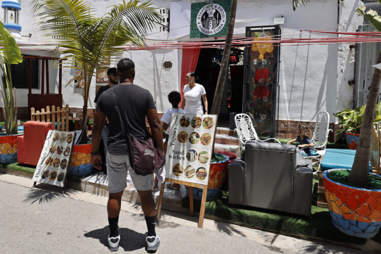 Personas pasando frente al restaurante Starcafe, en La Habana. Foto:  Ernesto Mastrascusa/EFE.