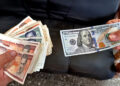 Imagen que simula una transacción en el mercado informal de divisas en Cuba, en el que el dólar ha mantenido un ascenso progresivo a lo largo de 2025 hasta superar los 400 pesos de valor. Foto: Ernesto Mastrascusa / EFE.
