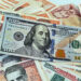 Un billete de 100 dólares junto a billetes de varias denominaciones de pesos cubanos. Foto: Ernesto Mastrascusa / EFE.