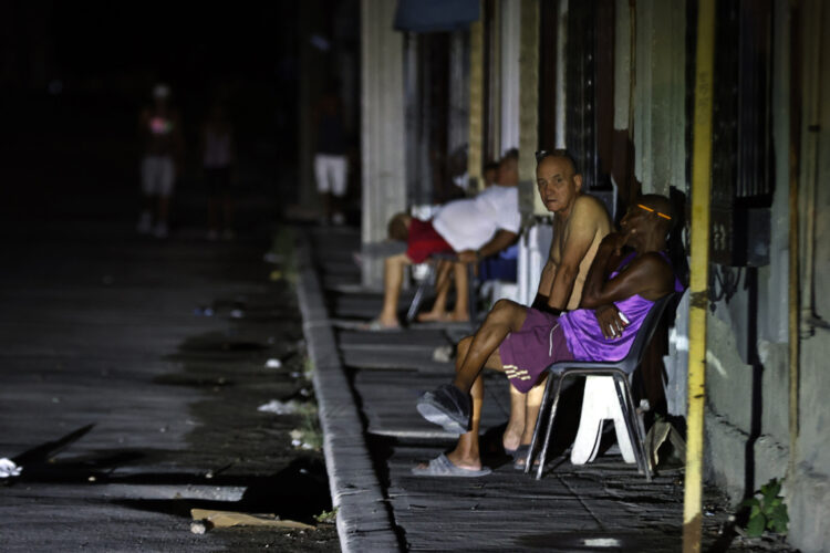 Personas sentadas fuera de sus casas durante un apagón nocturno en La Habana. Foto: Ernesto Mastrascusa / EFE.