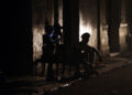 Personas sentadas en una acera esperan el regreso de la electricidad, en medio de un apagón en La Habana. Foto: Ernesto Mastrascusa / EFE.
