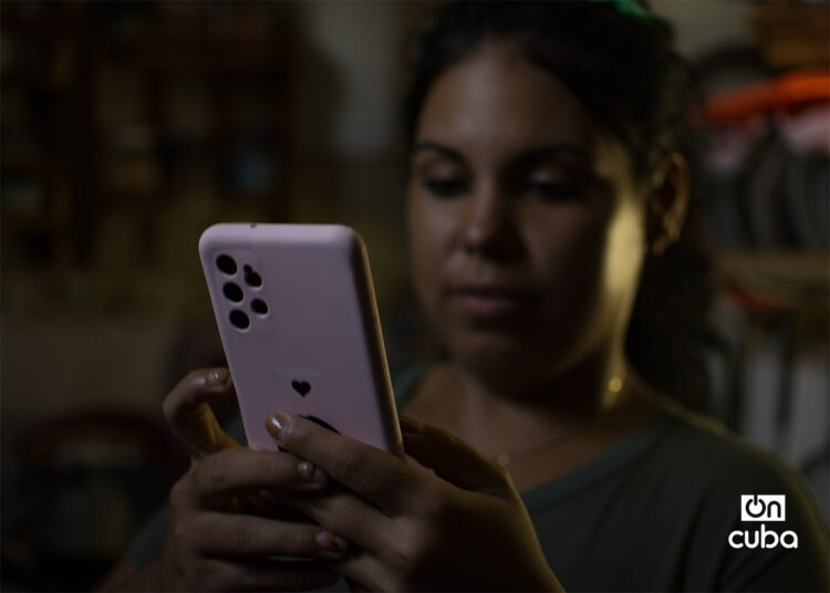 Una joven revisa su teléfono celular durante un apagón en La Habana. Foto: Otmaro Rodríguez.