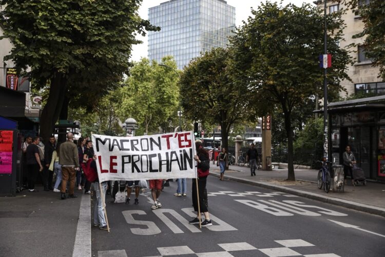 Un grupo de manifestantes en Francia exhibe una pancarta en la que piden la renuncia del presidente Emmanuel Macron. Foto: Teresa Suárez / EFE / EPA.