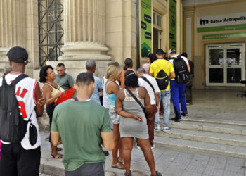 Personas hacen cola para acceder a los cajeros electrónicos de un banco, en La Habana. Foto: Ernesto Mastrascusa / EFE.