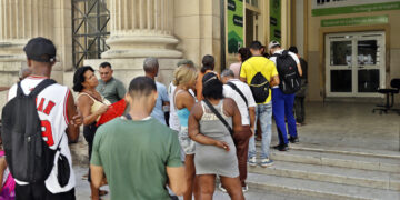 Personas hacen cola para acceder a los cajeros electrónicos de un banco, en La Habana. Foto: Ernesto Mastrascusa / EFE.