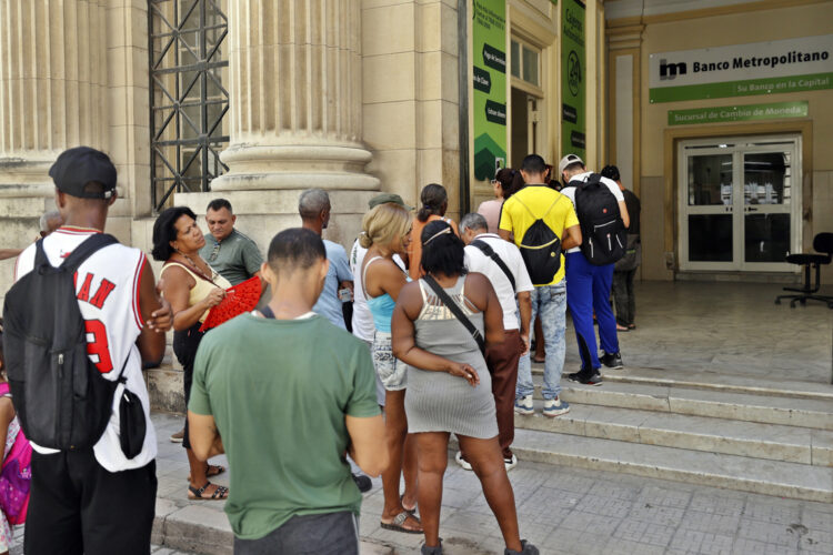 Personas hacen cola para acceder a los cajeros electrónicos de un banco, en La Habana. Foto: Ernesto Mastrascusa / EFE.