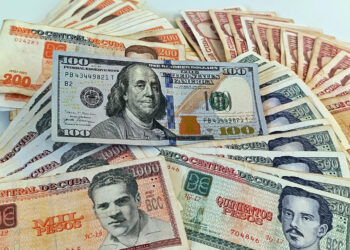 Un billete de 100 dólares junto a billetes de varias denominaciones de pesos cubanos. Foto: Ernesto Mastrascusa / EFE.