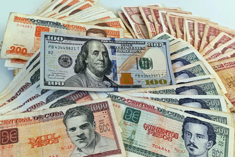 Un billete de 100 dólares junto a billetes de varias denominaciones de pesos cubanos. Foto: Ernesto Mastrascusa / EFE.