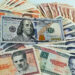 Un billete de 100 dólares junto a billetes de varias denominaciones de pesos cubanos. Foto: Ernesto Mastrascusa / EFE.