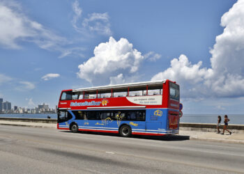 Un ómnibus de turismo transita prácticamente sin turistas por una zona del malecón habanero. Foto: Ernesto Mastrascusa / EFE.