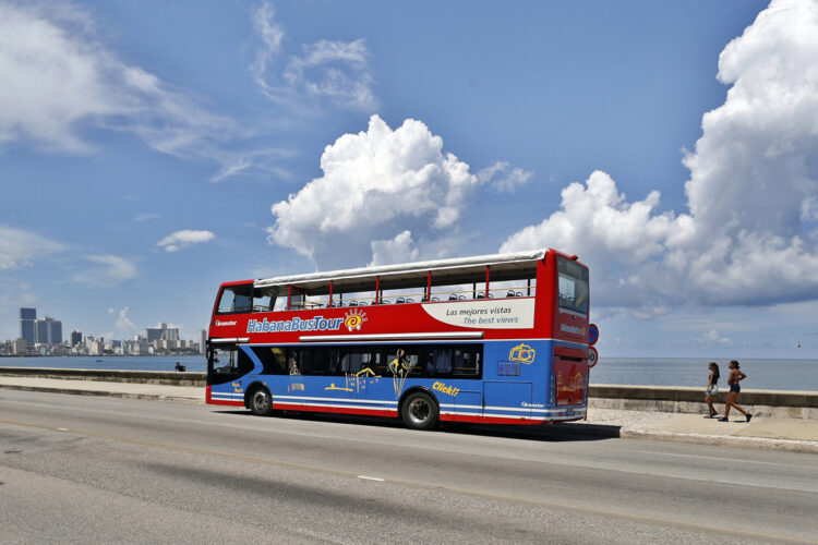 Un ómnibus de turismo transita prácticamente sin turistas por una zona del malecón habanero. Foto: Ernesto Mastrascusa / EFE.