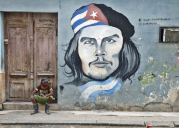 Un hombre descansa cerca de una pintura del Che Guevara en La Habana. Foto: Ernesto Mastrascusa / EFE.