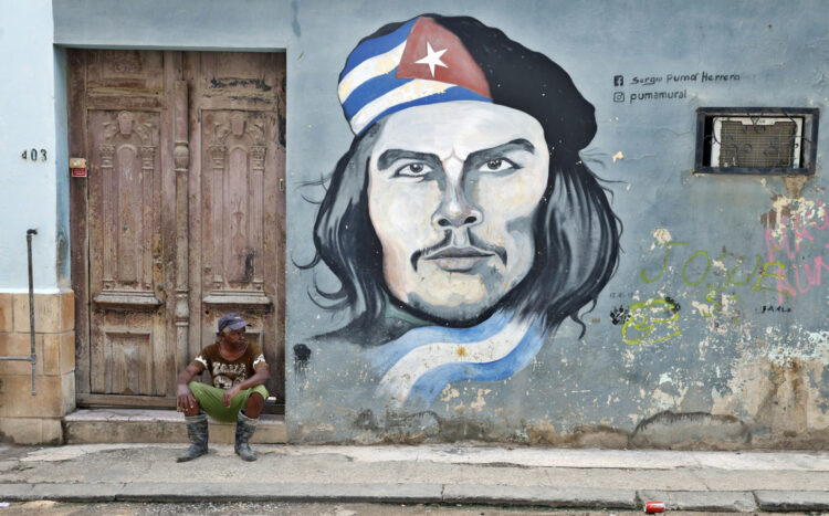 Un hombre descansa cerca de una pintura del Che Guevara en La Habana. Foto: Ernesto Mastrascusa / EFE.